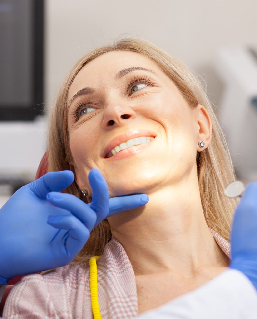 A young woman smiling up from a dental chair at esteem dental studio