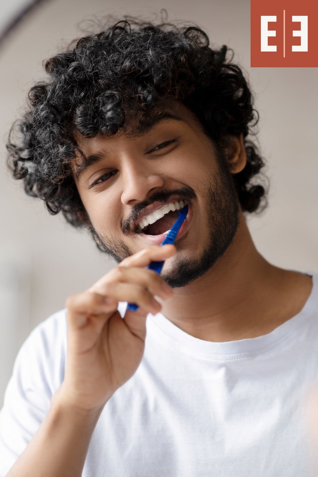 A young curly haired man brushing his teeth at esteem dental studio