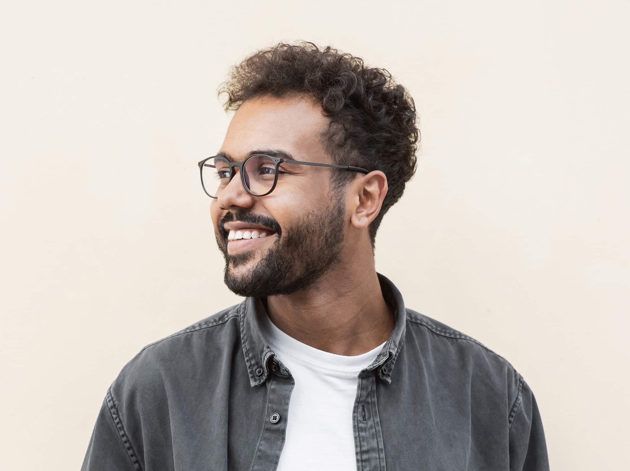 man with glasses smiling looking off to side - Esteem Dental Studio