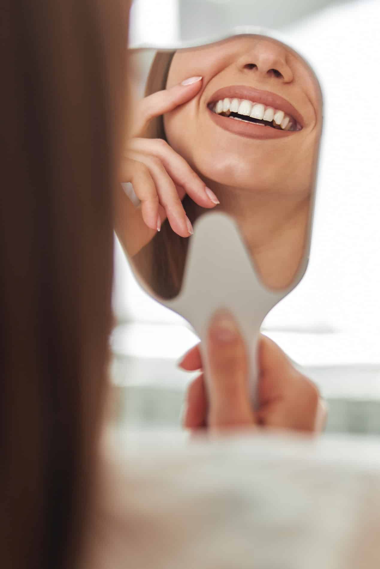 Woman looking at their teeth whitening results in Powder Springs GA