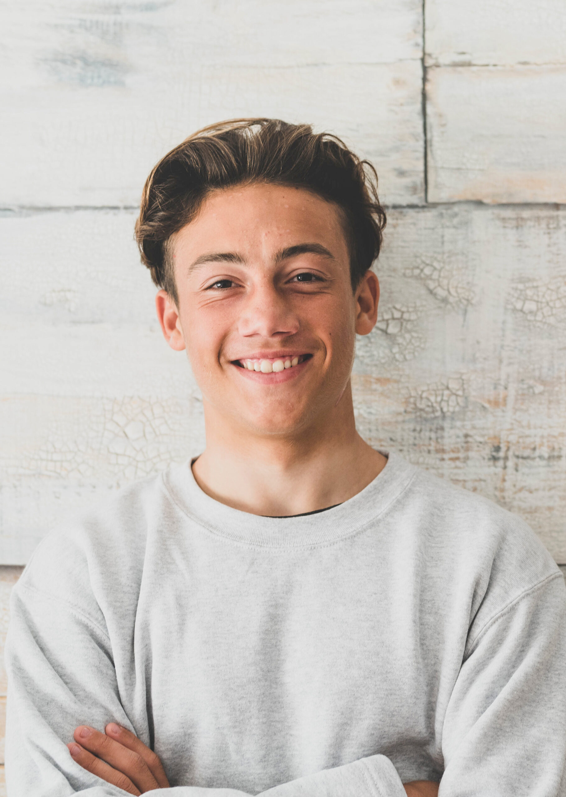 one teenager at home smiling happy at the camera - simple photo of handsome young man looking with wooden wall at the background